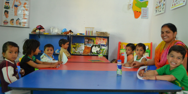 Pre-schooled Kids Sitting Around The Table With Their Teacher To Learn Emotions.