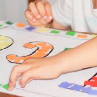 A Preschooled Kid Doing Coloring Activity In His Chartpaper.