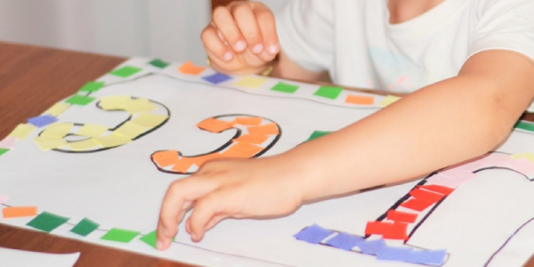 A Preschooled Kid Doing Coloring Activity In His Chartpaper.