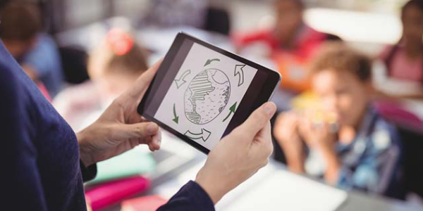 A Teacher Holding Tablet And Teaches The Kids.