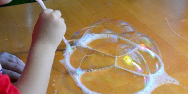 A Small Kid Playing With Bubble Blower.