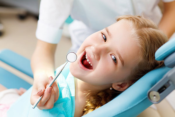 A Little Girl facing towards the camera by opening her mouth for her oral treatment Sitting in a dental clinic.